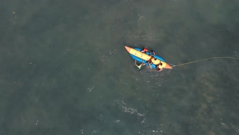 Aerial-birds-eye-spinning-shot-of-people-trying-to-climb-banana-boat