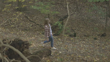 Wide-shot-of-a-young-woman-walking-down-a-trail-in-the-woods