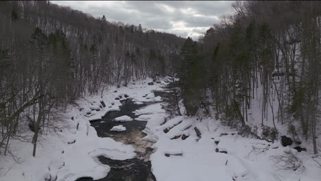 Aerial-scenic-drone-down-motion-Canadian-wilderness-mid-winter-near-north-Quebec-Stoneham-Ski-Resort-of-frozen-over-Sautaurski-River