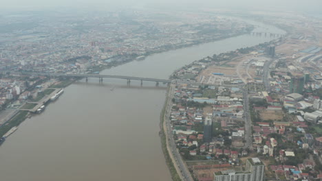 Slow-Aerial-pan-over-Phnom-Penh-and-Tonle-Sap-its-Bridge-on-a-polluted-day
