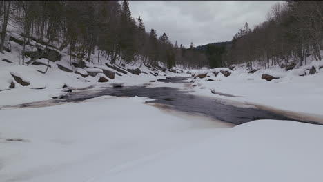 Aerial-scenic-drone-forward-Canadian-wilderness-mid-winter-near-north-Quebec-Stoneham-Ski-Resort-of-frozen-over-Sautaurski-River-cold-cloudy