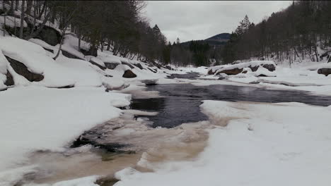 Luftbilddrohne,-Vorwärtsbewegung,-Kanadische-Wildnis,-Mitten-Im-Winter,-In-Der-Nähe-Des-Skigebiets-Stoneham-Im-Norden-Von-Quebec,-Gefroren-über-Dem-Sautaurski-Fluss-Flussaufwärts