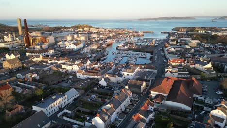 Flight-over-St-Sampson-Guernsey-from-Leale’s-yard-to-the-sea-showing-urbanisation,marina,-boatyard,power-station,-ship,docks-cranes,-Vale-Castle-and-views-out-to-sea-and-Herm-on-calm-sunny-day