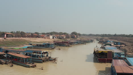 Low-flying-shot-along-muddy-river-with-fisherman-boats-in-Cambodia