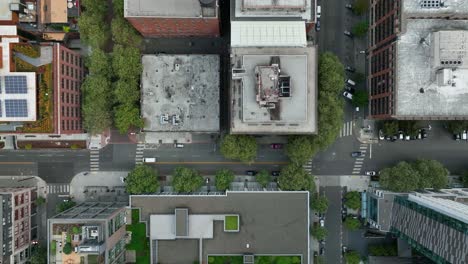 Top-down-aerial-view-of-cars-a-white-car-driving-through-Seattle's-downtown-streets