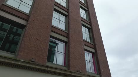 Aufsteigende-Luftaufnahme-Eines-Backsteingebäudes-Mit-Glasfenstern-In-Der-Innenstadt-Von-Seattle
