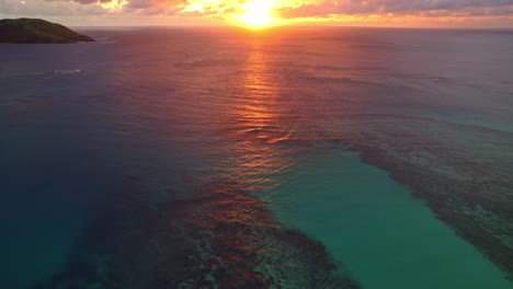 Vibrant-golden-sunset-over-water-and-coral-reef,-Yasawa,-Fiji,-reveal-shot