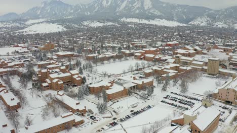 Beautiful-aerial-tilt-up-shot-showing-snowy-city-of-Boulder-in-Colorado-with-snowy-mountains-in-background