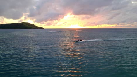 People-cruising-on-tender-boat-during-a-vibrant-golden-sunset,-Yasawa,-Fiji