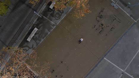 Aerial-top-down-view-of-a-person-lying-on-an-urban-basketball-court-at-sunset-in-Germany