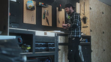 Caucasian-bearded-man-working-on-the-wood-plank-measuring,-indoor-workshop