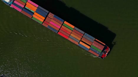 Huge-cargo-vessel-top-down-aerial-view-navigating-through-the-canal-in-Dordrecht,-The-Netherlands