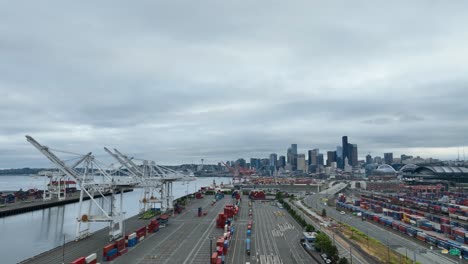 Wide-aerial-view-of-Seattle's-vacant-shipyard-with-clouds-and-city-skyscrapers-in-the-distance