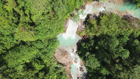Drohnenanflug-Kopfaufnahme-Eines-Himmelblauen-Wasserfalls-Im-Tiefen,-Dichten-Wald