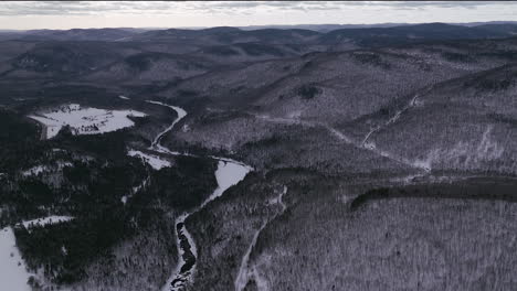 Aerial-scenic-drone-forward-motion-Canadian-wilderness-mid-winter-near-north-Quebec-Stoneham-Ski-Resort-of-frozen-over-Sautaurski-River-upstream-National-Park-Jacques-Cartier