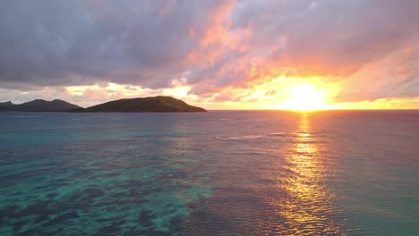 Vibrant-golden-sunset-over-water-and-coral-reef,-Yasawa,-Fiji,-Parallax-shot