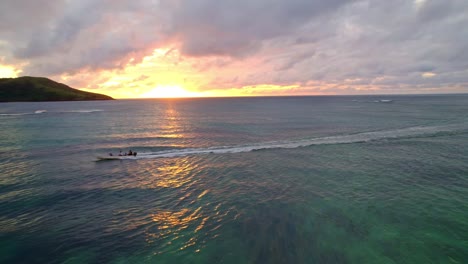 People-waving-from-tender-boat-cruising-off-during-a-golden-sunset,-Yasawa,-Fiji