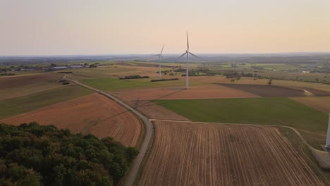 Aerial-dolly-in-towards-set-of-wind-turbines-rotating-in-France-at-sunset