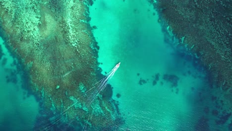 Birdseye-view-boat-cruising-over-turquoise-coral-reef,-yasawa-Islands,-Fiji
