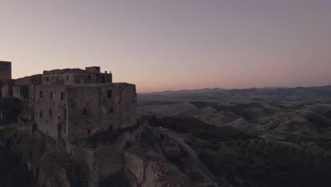 Drone-flying-in-circulair-motion-around-the-ruins-of-Craco-in-the-south-of-Italy-in-the-very-early-morning-sunrise-in-4k