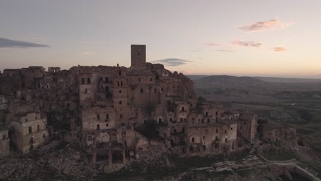 Drone-flying-backwards-away-from-the-ruins-of-Craco-on-a-hill-in-the-south-of-Italy-at-sunrise-in-4k