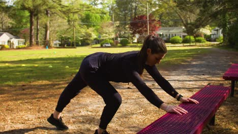 A-young-woman-dressed-in-all-black-takes-time-to-stretch-before-an-outdoor-workout-at-al-local-park