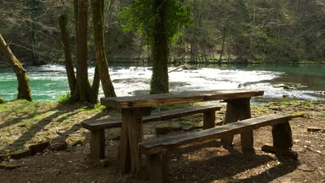 Static-shot-of-a-small-wooden-picnic-table-at-the-side-of-the-Krka-River