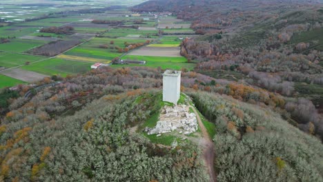 Aerial-pullback-reveals-castle-tower-da-pena,-xinzo-de-limia,-ourense,-spain,-fields-behind