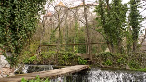 Static-low-angle-shot-of-a-wooden-bridge-across-a-small-waterfall-on-the-Krka-river