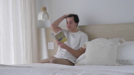 Guy-Read-Book-While-Sitting-An-Leaning-On-The-Headboard-Of-A-Bed