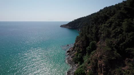 Drone-View-Of-A-Steep-Seaside-Rock-Near-Paradise-Beach,-Surrounded-By-Green-Vegetation,-Thassos-Island,-Greece,-Mediterranean-Sea,-Europe