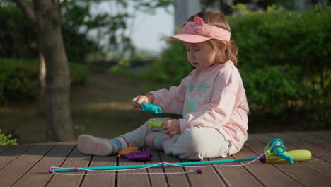 Young-girl-playing-with-toy-fishing-set-while-sitting-on-deck