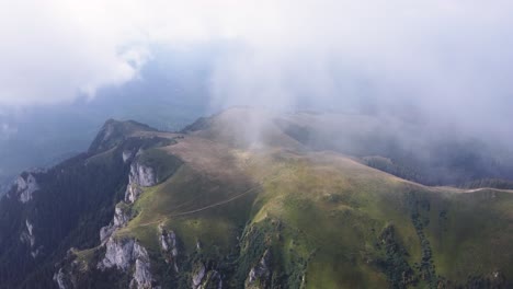Experience-the-mystique-of-a-mountain-peak-covered-in-summer-mist,-captured-from-a-mesmerizing-drone's-perspective