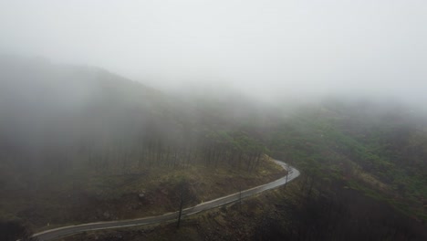 Dangerous-mountain-road-on-foggy-horror-day,-scary-scene,-aerial-view