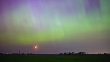 Aurora-borealis-lights-the-nighttime-sky-as-the-crescent-moon-sets-below-the-horizon---time-lapse