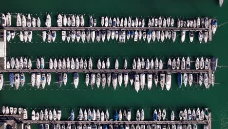 Aerial-top-down-view-of-sailboat-yacht-docked-in-parallel-row-in-a-harbor