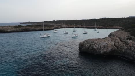 Aerial-drone-view-of-boats-in-Cala-Varques-beach,-Mallorca,-Spain