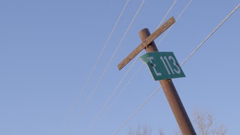 Telephone-pole-E113-sign-against-a-perfect-blue-sky-in-Texas-countryside