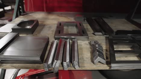 Sheets-and-parts-of-metal-pieces-precut-with-laser,-stored-on-a-shelf-in-workshop