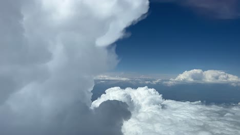 Impresionante-Vista-Desde-Una-Cabina-De-Jet-Mientras-Volaba-Junto-A-Una-Amenazadora-Nube-Cumulonimbus-De-Tormenta-A-12000m-De-Altura-En-Un-Día-Soleado-Con-Un-Cielo-Azul-Profundo