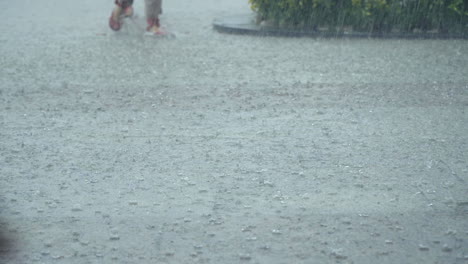 Pedestrians-walking-through-heavy-tropical-rainfall,-people-stepping-over-ground-fully-covered-with-water-on-strong-rainy-day