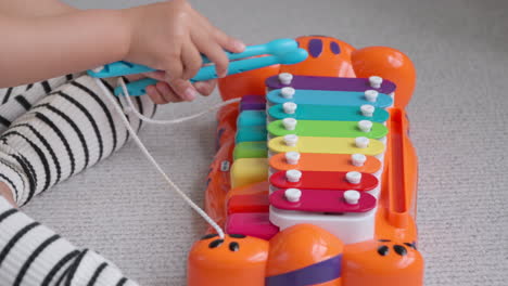 Nahaufnahme-Der-Hände-Eines-Kleinen-Aktiven-Mädchens,-Das-Auf-Einem-Spielzeugklavier-Und-Einem-Xylophon-Musikinstrument-Für-Kinder-Spielt,-Die-Zu-Hause-Auf-Dem-Boden-Sitzen-–-Zeitlupe