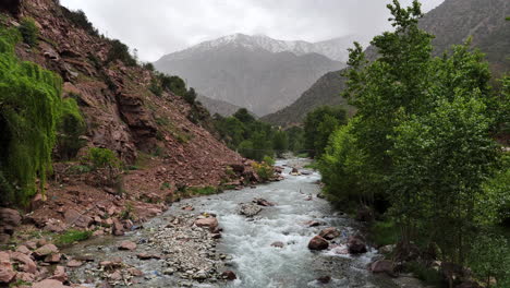 Cinematic-landscape-with-creek,-Atlas-Mountains-in-background,-Morocco
