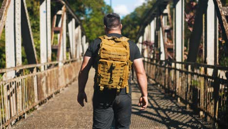 Young-traveler-walking-on-rusty-old-bridge-outdoors-on-beautiful-sunny-summer-day