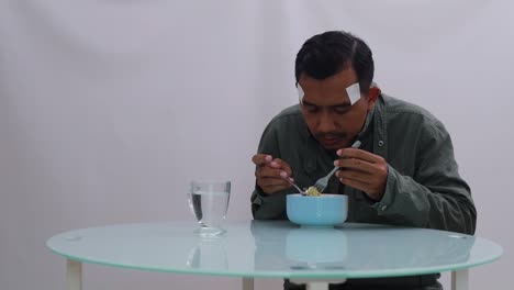 Asian-man-in-jacket-shivering-while-eating-boiled-noodles-on-the-table