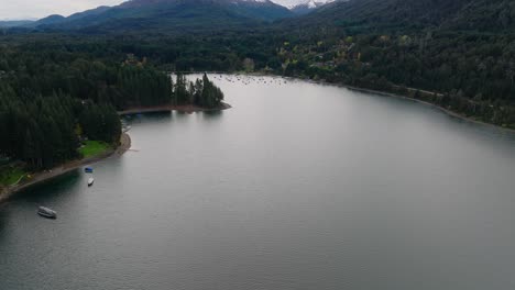 Vuelo-Aéreo-Sobre-El-Lago-Nahuel-Huapi-En-San-Carlos-De-Bariloche-Con-Inclinación-Hacia-Arriba-Revelando-Una-Montaña-Cubierta-De-Nieve-En-El-Fondo