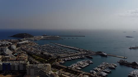 Drone-panning-along-the-horizon,-marina-and-town-of-Ibiza