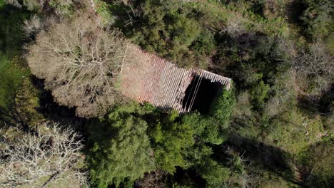 Aerial-rotating-rising-shot-of-a-destroyed-roof-on-a-small-outhouse