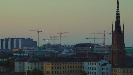 Aerial-sunset-shot-of-Riddarholm-church-with-construction-cranes-in-background