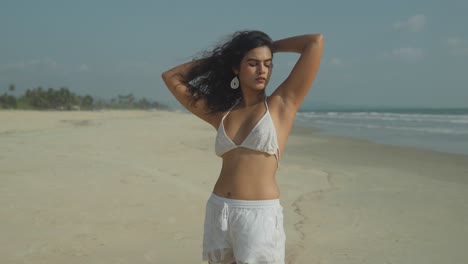 Female-south-asian-woman-modelling-white-bikini-swimwear-for-fashion-photoshoot-on-sunny-beach